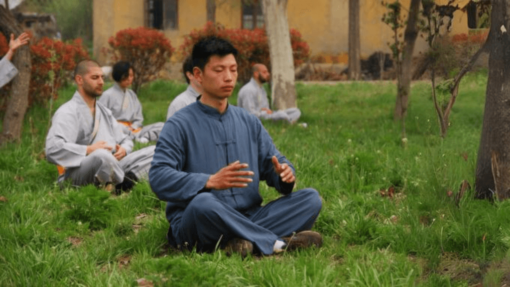 Master Tang meditating with students outdoors