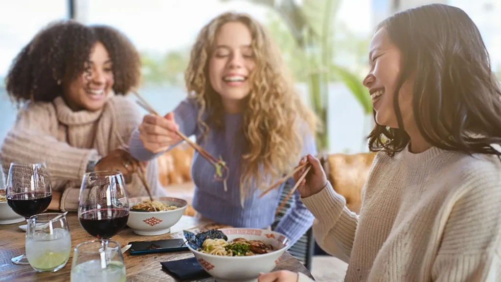 Asian women with white and black women sharing Chinese food