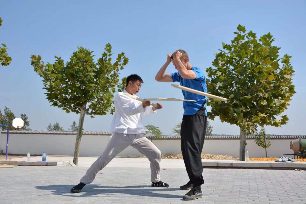 kung fu master and student hard qi gong, hitting student with stick