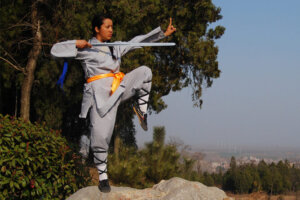 kung fu students Terya posing with a sword in the mountains