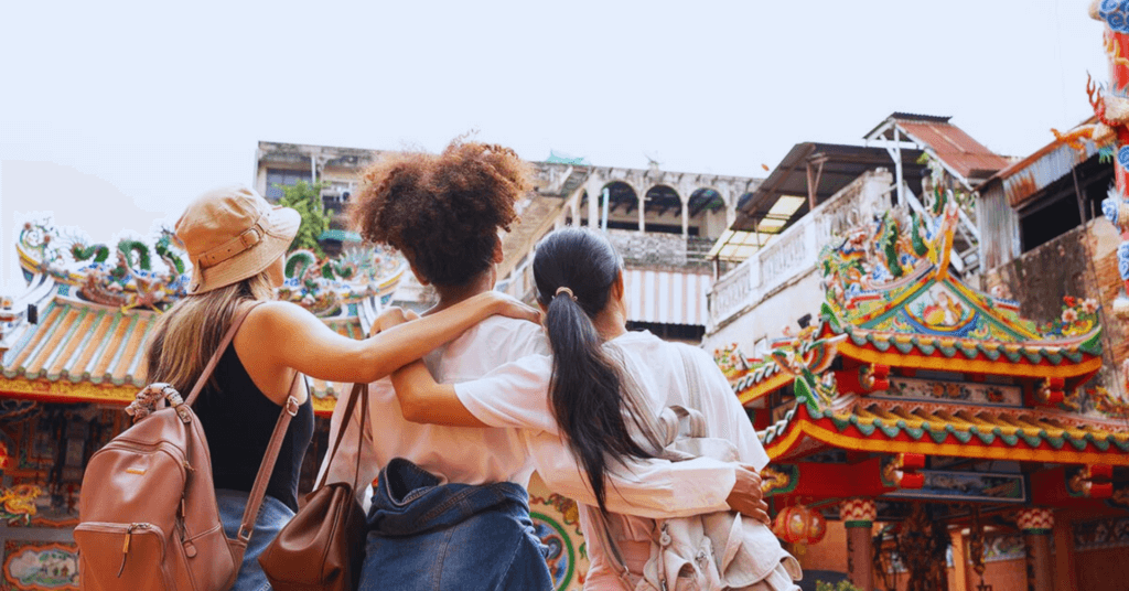 Three foreigner friends with arms across each others' shoulders looking at a Chinese temple.